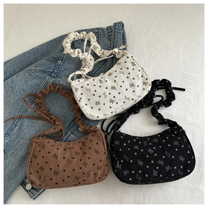 Detailed view of pleated corduroy bags with floral bow prints in white, brown and black