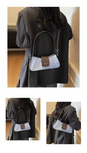 Detail of blue denim baguette bag with brown leather trim and shoulder strap