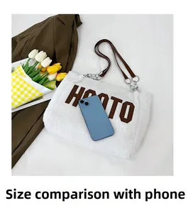 Close-up of white plush tote bag with HOTO letter print and mobile phone for size scale