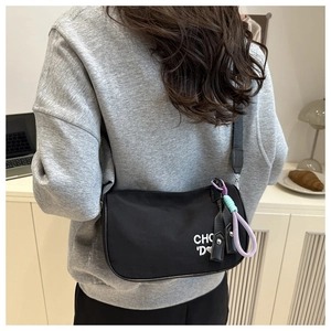 Détail du sac demi-lune en nylon noir avec broderie de lettres et cordon tressé coloré