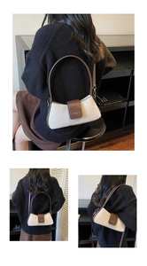 Detail of cream leather shoulder bag showing contrast brown trim and adjustable strap