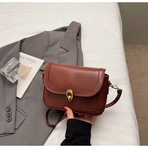 Retro reddish-brown leather square bag with gold ring buckle on white linen setup