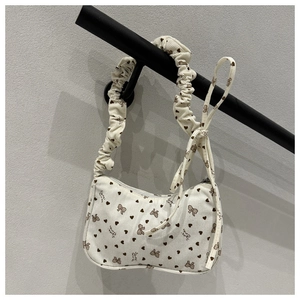 Detail of cream corduroy bag featuring brown bows and ruched drawstring shoulder strap
