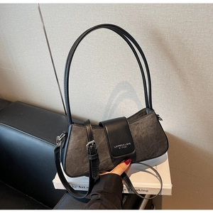 Detail shot of the dark grey textured fabric and leather strap on the baguette bag