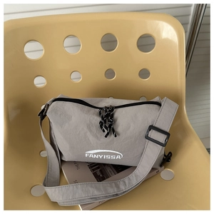 Detail of grey nylon crossbody bag with brand logo on a yellow chair background