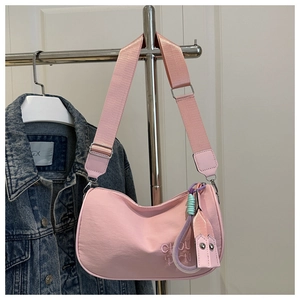 Sac polochon rose avec broderie et large bandoulière suspendu à un cintre avec veste
