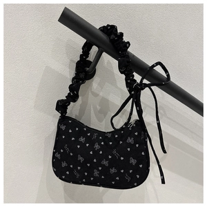 Close-up of black pleated handbag with white bow and heart prints and Sweet Honey text