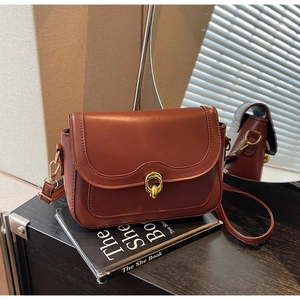 Detail view of reddish-brown leather bag with golden twist-lock and fine stitching
