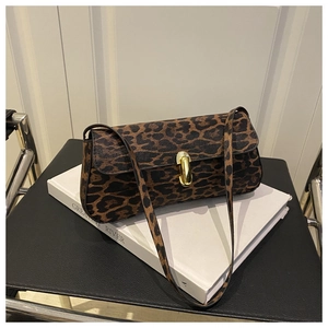 Detail shot of leopard print shoulder bag featuring a gold twist lock on a white book