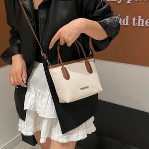 Sac seau chic en cuir beige et marron porté en bandoulière et à la main par un mannequin