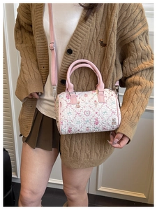 Détail du sac cylindre rose à relief ours porté avec un gilet en maille marron