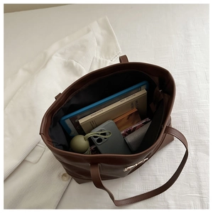 Internal view of large brown leather tote bag with tablet, books, and accessories