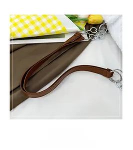 Close-up of brown leather shoulder strap with silver metal buckle on a white fuzzy tote bag