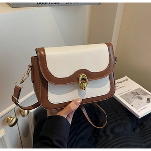 Detail view of contrast color crossbody bag with gold ring buckle and leather strap