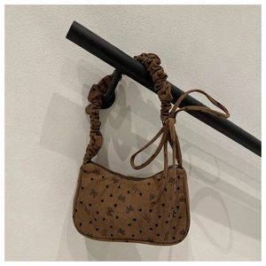 Detailed texture of brown corduroy bag with heart and bow patterns on a gathered handle