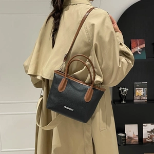 Sac seau noir pour femme avec poignées marron et lettrage fashion porté par un mannequin