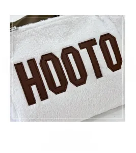 Close-up of brown HOOTO letter embroidery on white plush tote bag material