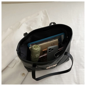 Macro shot of large black leather tote showing storage for tablets and umbrellas