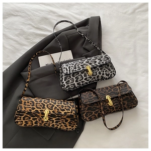Three leopard print shoulder bags in black, tan and brown with gold buckles on grey fabric