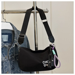 Détail du sac à bandoulière noir brodé avec sangle tressée et accessoire coloré