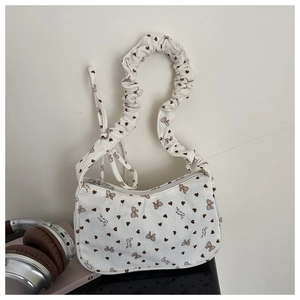Detailed texture of white corduroy bag featuring brown heart prints and pleated strap
