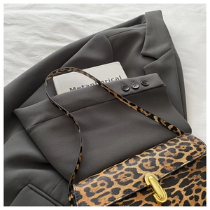 Close-up of leopard print baguette bag with gold buckle on grey blazer