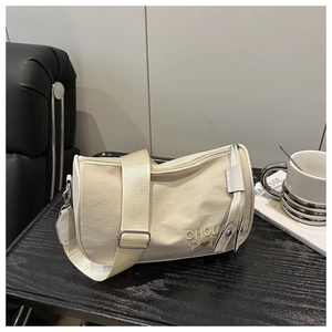 Détail du sac cylindre crème avec broderie CHOU et large bandoulière réglable