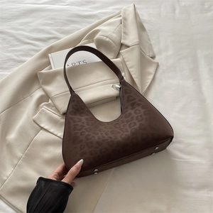 Vintage leopard print shoulder bag with crescent shape and metallic base studs on beige fabric