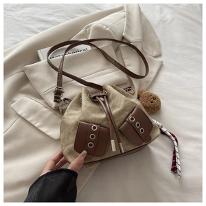 Detail of canvas drawstring bucket bag with leather trim and cute bear keychain charm
