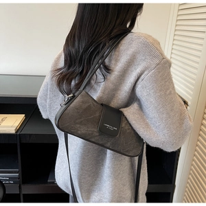 Detail of dark grey vintage baguette bag with black leather flap and shoulder strap