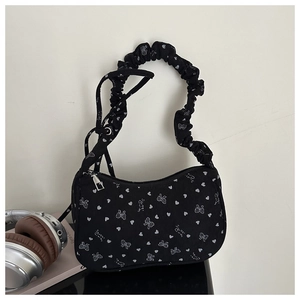Close-up of black pleated handle handbag with white sweet girl bow and heart print