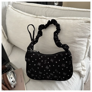 Detail of black corduroy shoulder bag featuring white heart and bow prints with sweet heart text