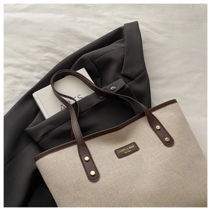 Detailaufnahme der beigen Canvas-Tasche mit braunem Lederbesatz und Goldnieten