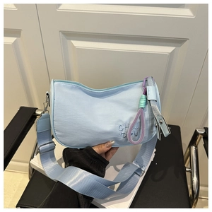 Détail du sac croissant bleu clair avec broderie de lettres et pendentif tressé