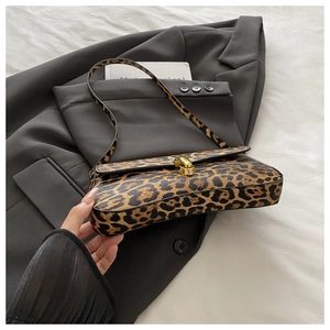 Close-up of leopard print baguette bag with a gold rectangular buckle on a grey blazer