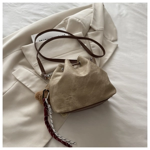 Detail of canvas drawstring bucket bag with leather strap and cute bear charm pendant