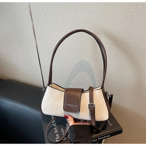 Detail showing cream textured fabric and brown leather handle of the chic baguette bag