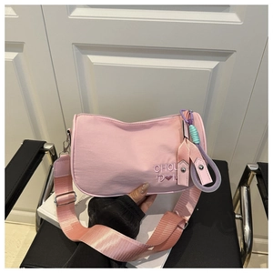 Détails de broderie sur un sac en nylon rose avec pendentif tissé et bandoulière