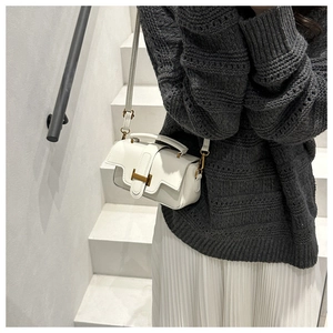 Detail der weißen Lederbox-Tasche mit goldener H-Schnalle, kombiniert mit einem Rock