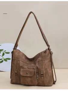 Close-up of vintage brown leather tote with front snap pocket and decorative rivets