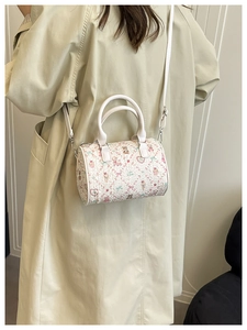 Détail du mini sac boston à imprimé dessin animé porté avec un trench beige