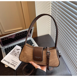 Close-up of brown baguette bag featuring a metal buckle and embossed logo detail