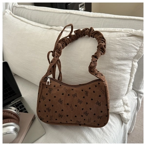 Close-up of brown corduroy hobo bag with heart bow patterns and ruched handle detail