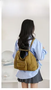 Detailed back view of a mustard yellow canvas backpack with multi-pocket design on model