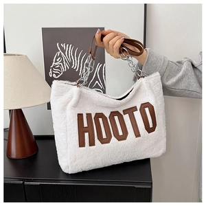 Detail of soft white faux fur tote bag featuring brown HOOTO patch and metal chain strap