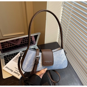 Detailed view of light blue denim baguette bag with dark brown leather flap and strap