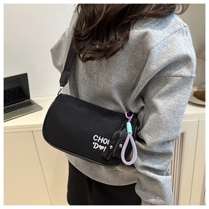 Gros plan du sac oreiller en nylon noir avec broderie blanche et breloques tissées