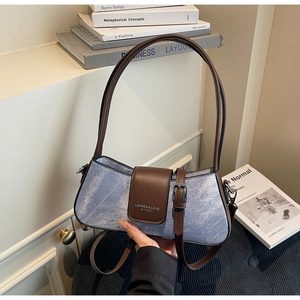 Detail of blue denim and brown leather baguette bag on aesthetic art books