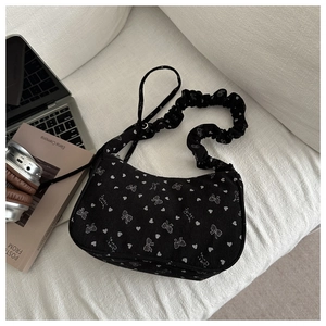 Detail of black corduroy shoulder bag with white bow patterns and ruched handle