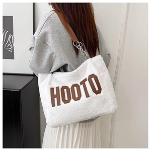 Detail of white plush tote bag with brown faux leather straps and metal chain accents